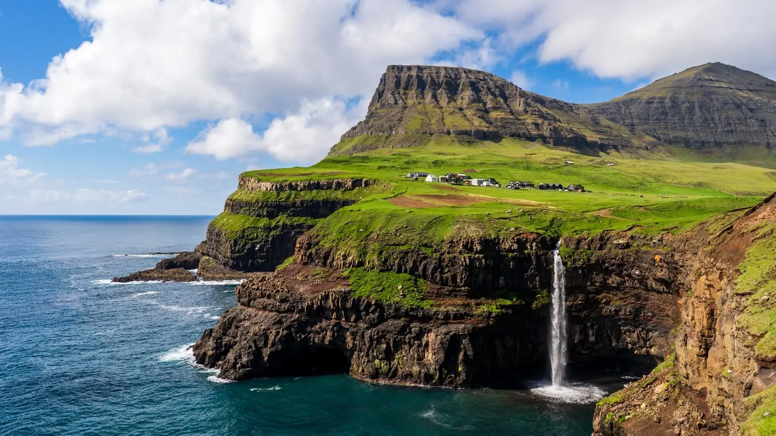Gásadalur village with Múlafossur Waterfall flowing into the Atlantic Ocean in daylight, Faroe Islands