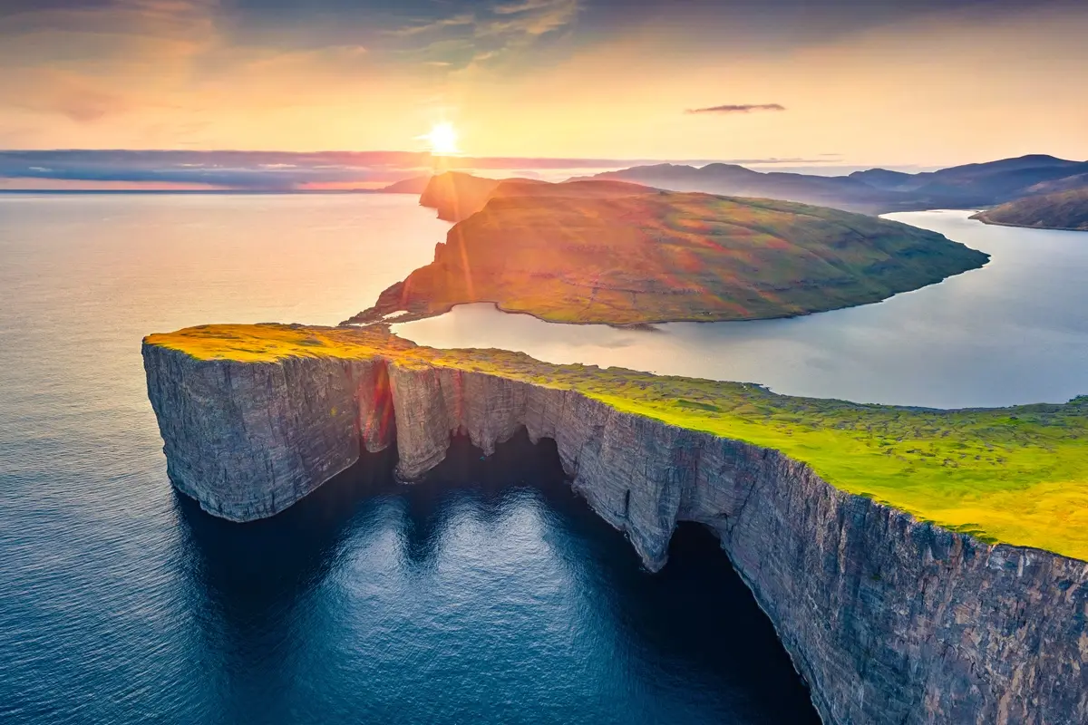 View from Trælanípa cliff looking down at Sørvágsvatn Lake above the ocean on a sunny day