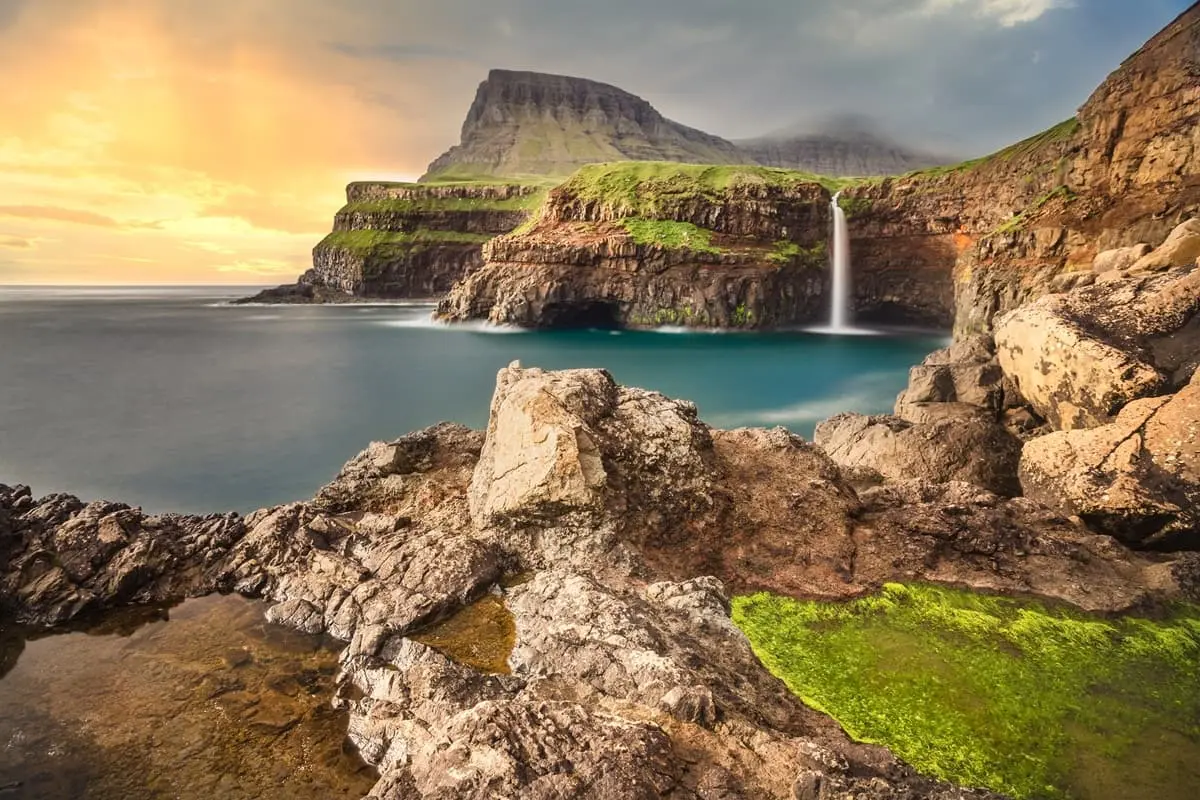 Múlafossur Waterfall plunging into the Atlantic, viewed from sea level in the Faroe Islands