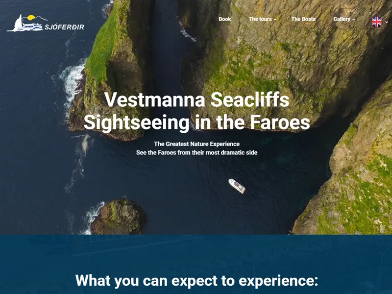 Boat cruising beneath the towering Vestmanna Seacliffs